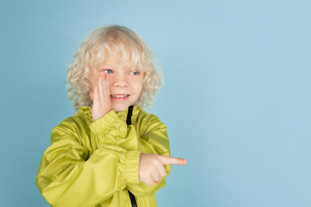 Portrait of beautiful caucasian little boy isolated on blue  wall