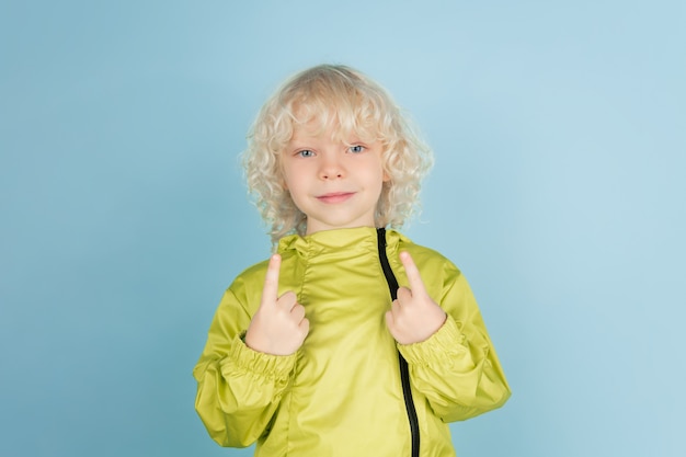 Portrait of beautiful caucasian little boy isolated on blue  wall