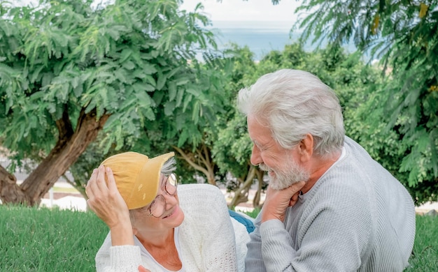 Portrait of beautiful Caucasian senior couple lying in public park relaxing and talking A happy elderly couple spend pleasant time together in the outdoors