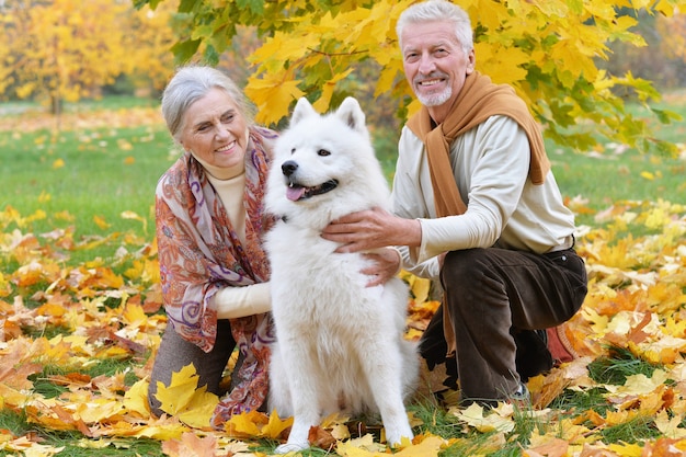 Portrait of beautiful caucasian senior couple with dog in autumn park