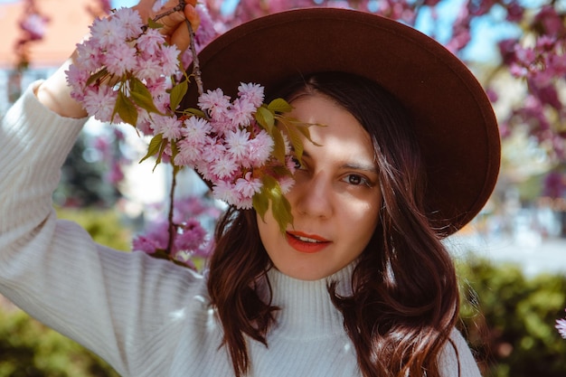 Portrait of beautiful caucasian woman with blooming sakura cherry trees copy space