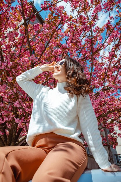 Portrait of beautiful caucasian woman with blooming sakura cherry trees copy space