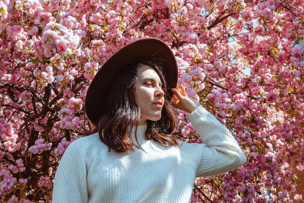 Portrait of beautiful caucasian woman with blooming sakura cherry trees