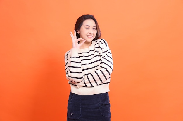 Portrait of a beautiful cheerful confident indonesia girl standing with arms crossed gesturing okay