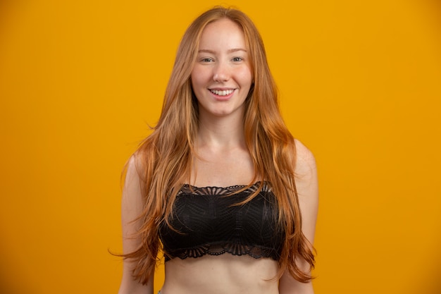 Photo portrait of beautiful cheerful redhead girl smiling laughing  over yellow wall