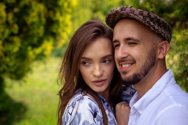 Portrait of beautiful couple in love both looking away and smiles outside