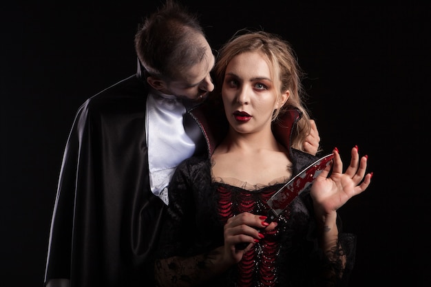 Photo portrait of a beautiful couple in medieval costumes with vampire style make-up for halloween. charming vampire woman.