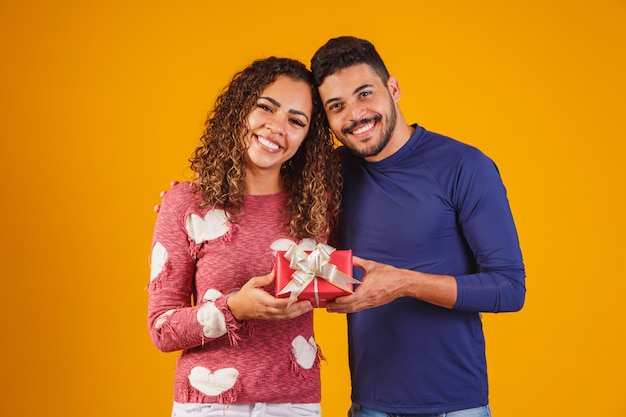 Portrait of a beautiful couple on yellow background with a gift