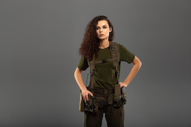 Portrait of beautiful curly brunette with serious expression on the face of female soldier