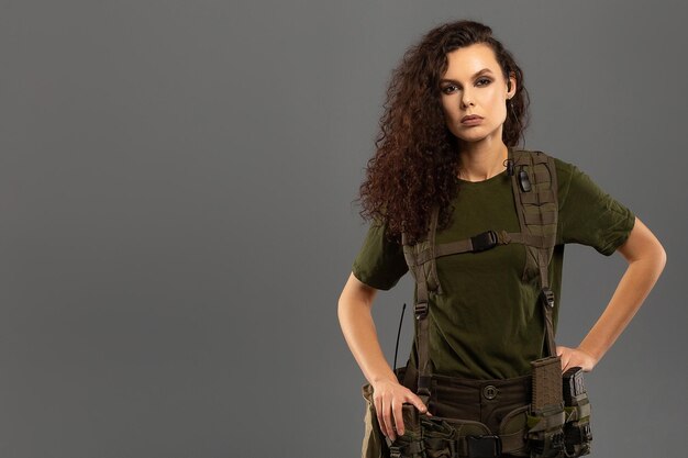 Portrait of beautiful curly brunette with serious expression on the face of female soldier