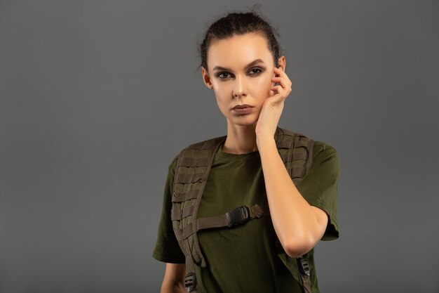 Portrait of beautiful curly brunette with serious expression on the face of female soldier