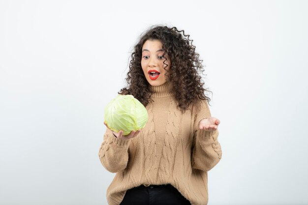 Portrait of beautiful curly woman holding green cabbage.