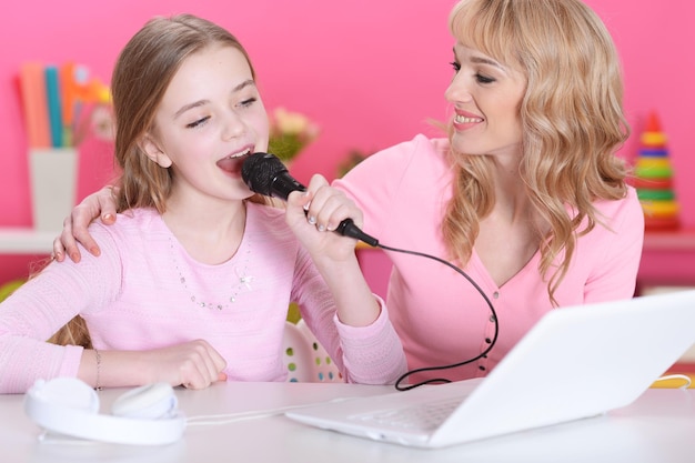 Portrait of beautiful cute girl sitting at table and singing karaoke