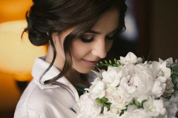 Ritratto di una bella sposa delicata in una camicia bianca con un bouquet da sposa