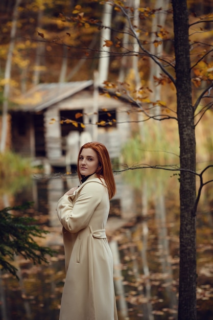 Portrait of a beautiful, dreamy and sad girl with red hair in white coat autumn