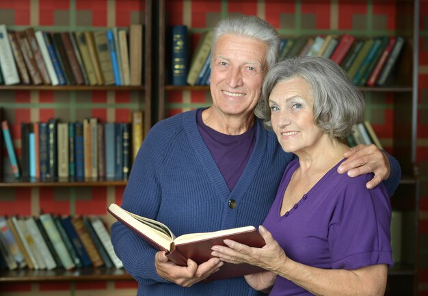 Portrait of beautiful elderly couple over book shelves