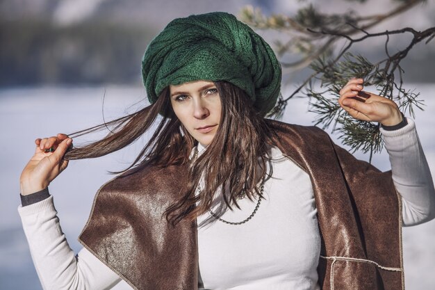 Portrait of a beautiful fashionable young woman in winter with a branch of a tree in a headdress