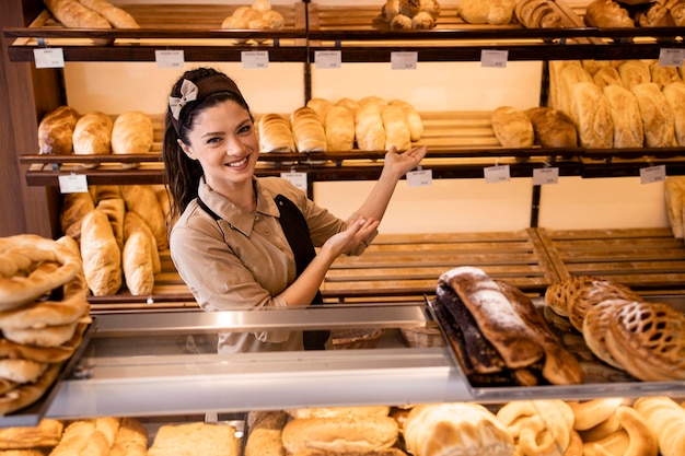 Ritratto di bella fornaia femminile in piedi nel negozio di panetteria