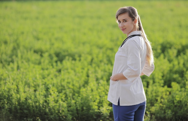 Portrait of a beautiful female doctor or nurse on green grass background