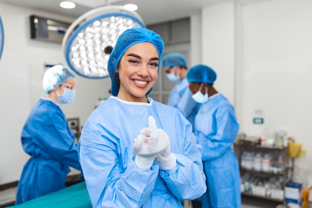 Ritratto di bella donna medico chirurgo che indossa guanti medicali in piedi nella sala operatoria.