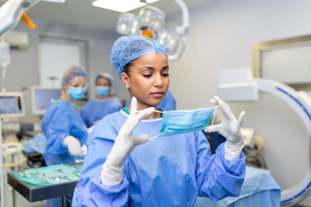 Portrait of beautiful female doctor surgeon putting on medical mask standing in operation room Surgeon at modern operating room