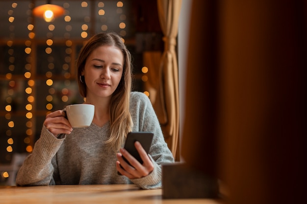 Bella femmina del ritratto che esamina cellulare