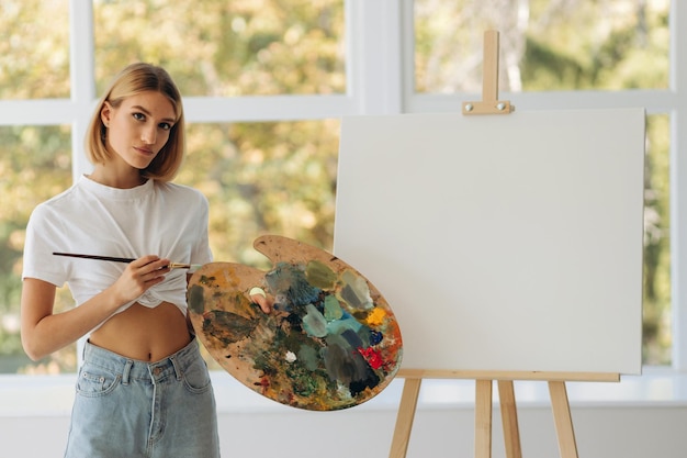 Portrait of beautiful fine artist with palette and paintbrush