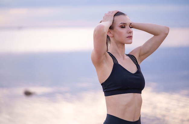 Ritratto di un bellissimo modello di fitness su uno sfondo del mare al tramonto