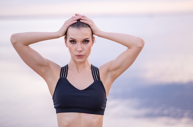 Ritratto di un bellissimo modello di fitness su una del mare al tramonto