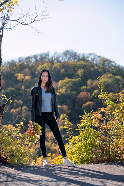 Portrait of beautiful girl on autumn park background. Young woman walks in the autumn park. Vertical frame.