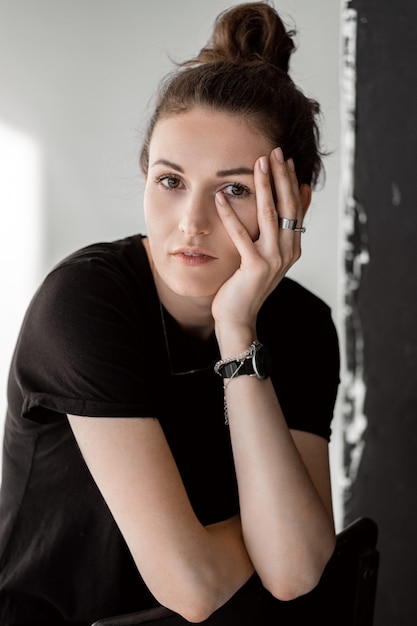 Portrait of a beautiful girl in a black shirt covers his face with his hand.