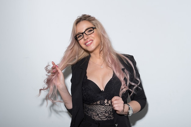 Portrait of a beautiful girl in a black suit against a white wall