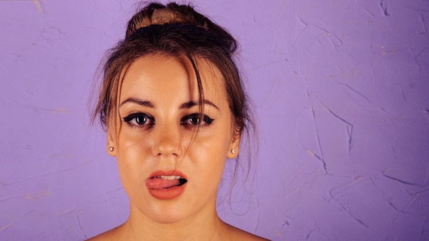 Photo portrait of beautiful girl on a blue background showing tongue