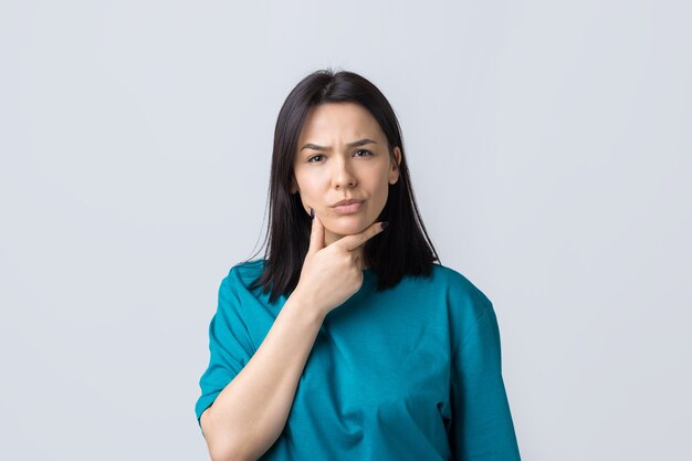 Portrait of a beautiful girl in a blue tshirt looks aside with pensive expression