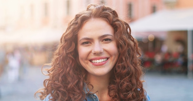 Portrait of beautiful girl of caucasian ethnicity with curly ginger hair standing on the warm spring...