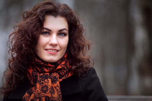 Portrait of a beautiful girl in a draped coat and a bright scarf