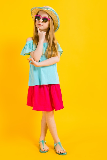 Portrait of a beautiful girl in a hat, sunglasses, summer dress and sandals.