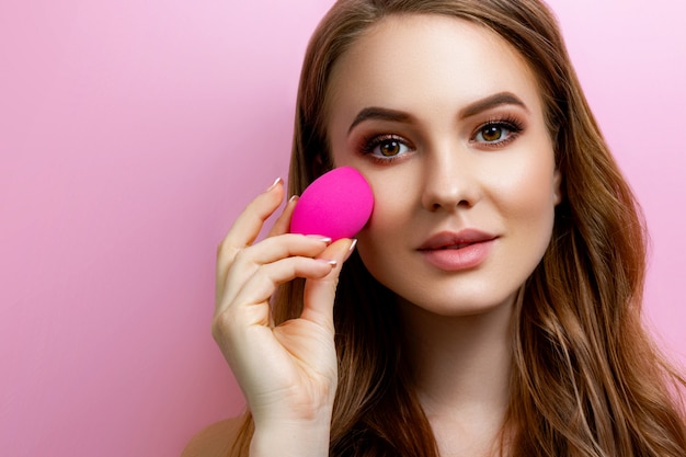 Photo portrait of a beautiful girl holding a beauty blender for make-up