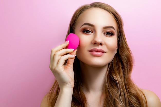 Portrait of a beautiful girl holding a beauty blender for make-up