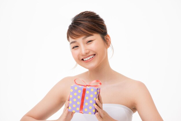 A portrait of beautiful girl holding a gift box isolated on white background