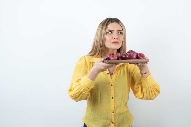 Portrait of beautiful girl holds red onions and smell them