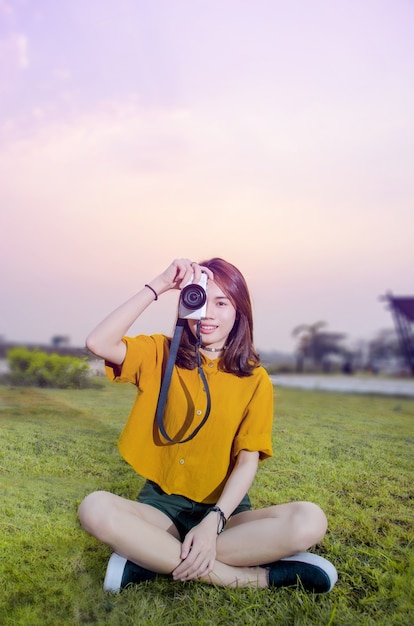 美しい少女の肖像画、カメラ付き夏の緑の公園で写真を撮る