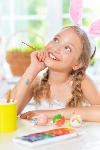 Portrait of beautiful girl painting eggs for Easter holiday