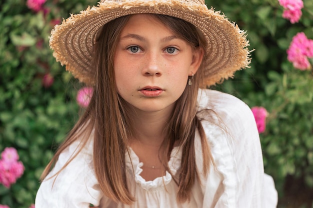 Portrait of a beautiful girl among pink roses outside