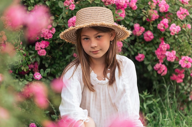 Portrait of a beautiful girl among pink roses outside