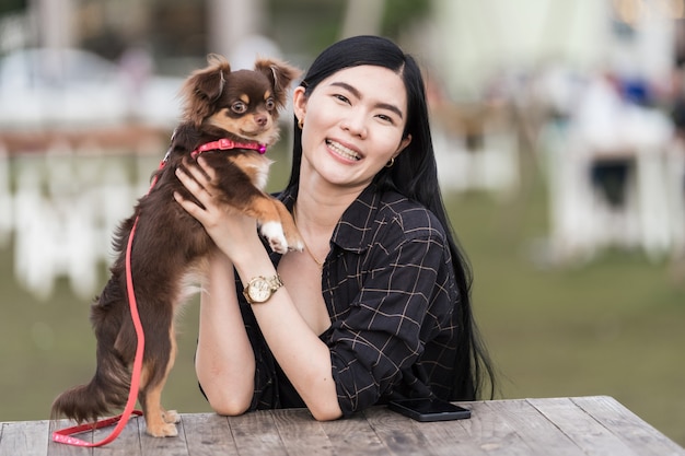 公共の公園の屋外で彼女の素敵な子犬と遊ぶ美しい少女の肖像画。飼い主のいる小さな犬が公園で遊んだり楽しんだりして一日を過ごします。ペット愛ストックフォト