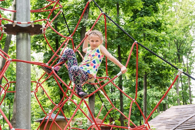 Portrait of a beautiful girl on a rope park among trees