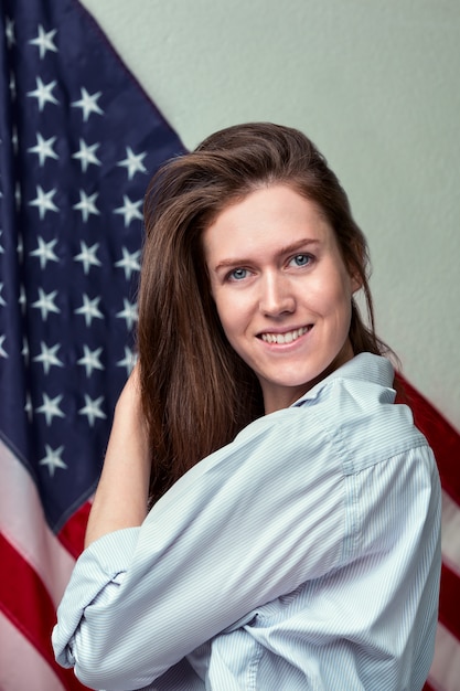 Portrait of beautiful girl in shirt on american flag wall close up