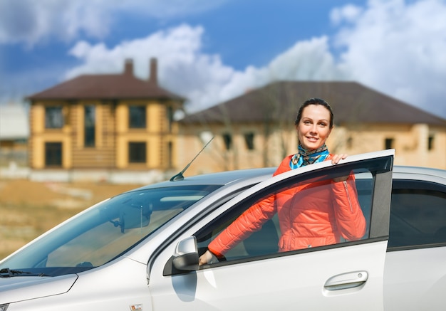 Portrait of a beautiful girl standing by car door open