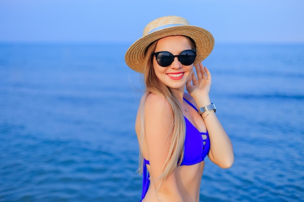 Portrait of a beautiful girl in sunglasses boater and blue swim